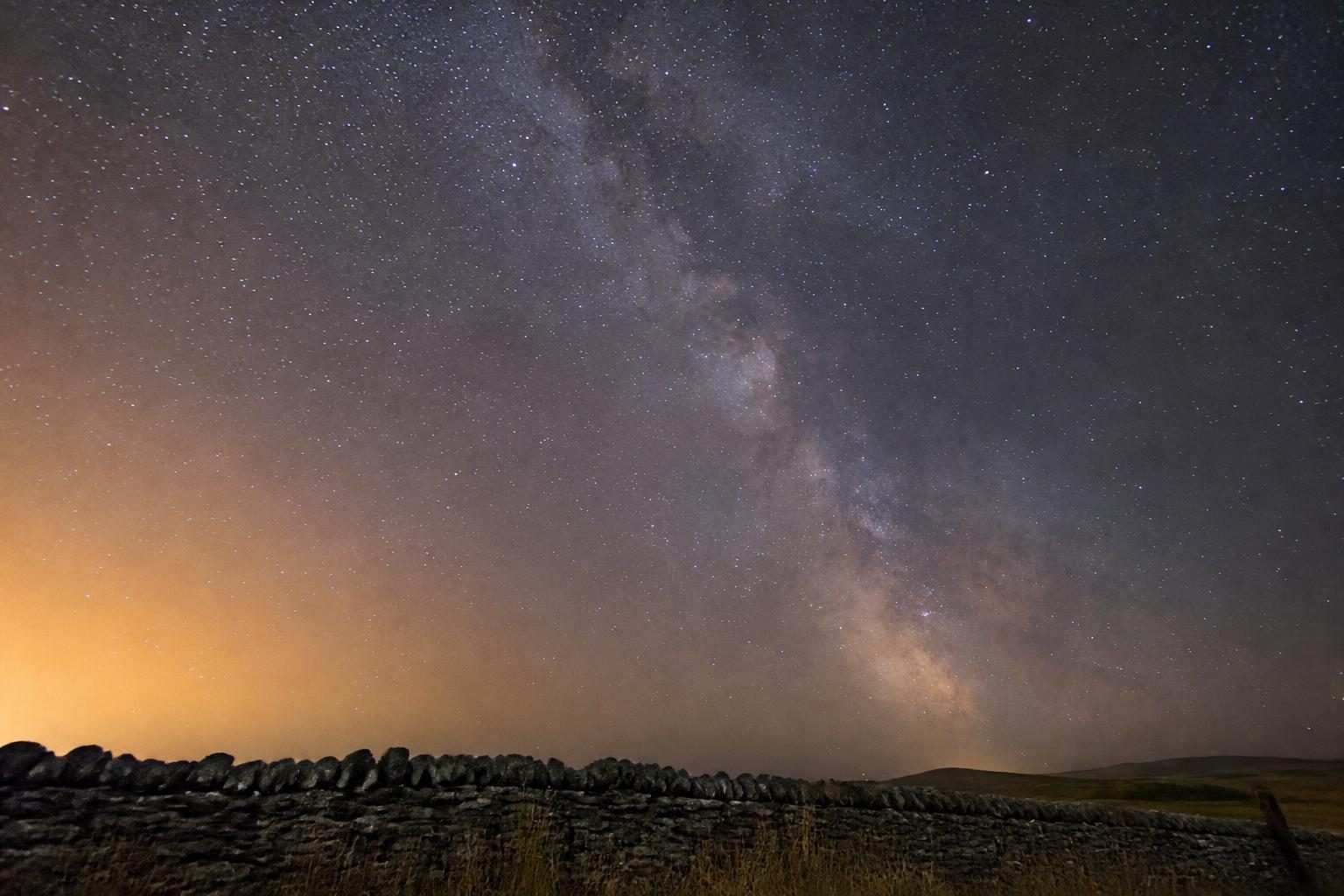 Stacked Milky Way core over a dry stone wall