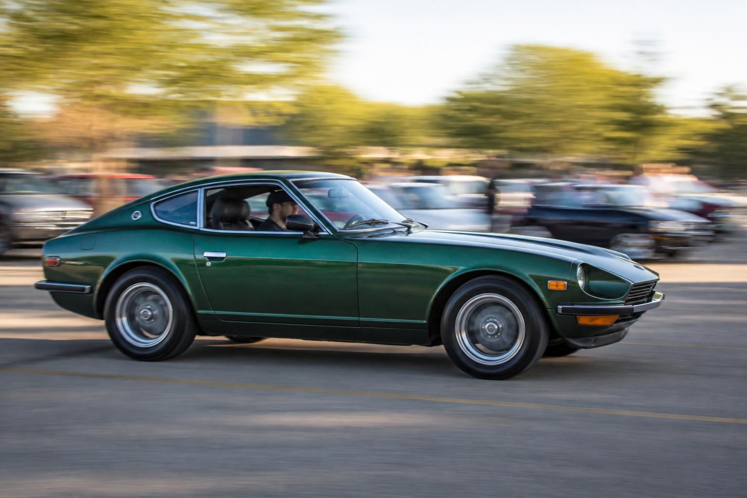 A green classic sports coupe in a panning shot