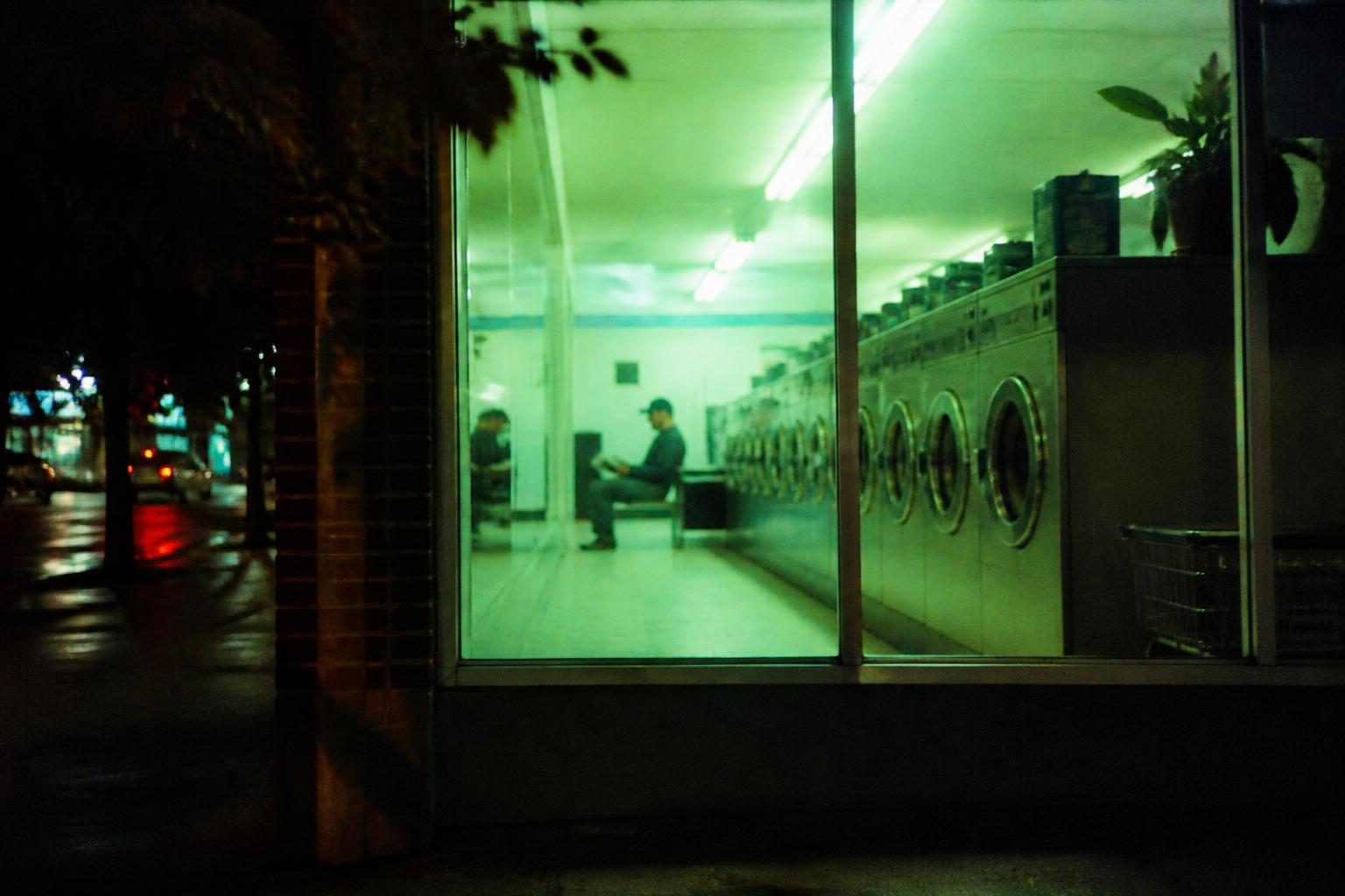 A laundromat window glowing green at night