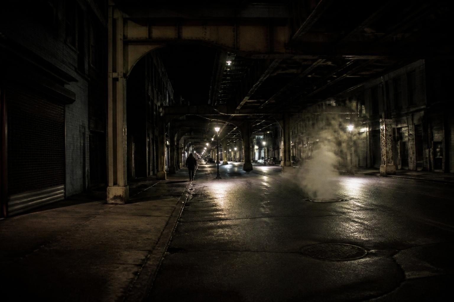 Moody city street at night with deep shadows and grain
